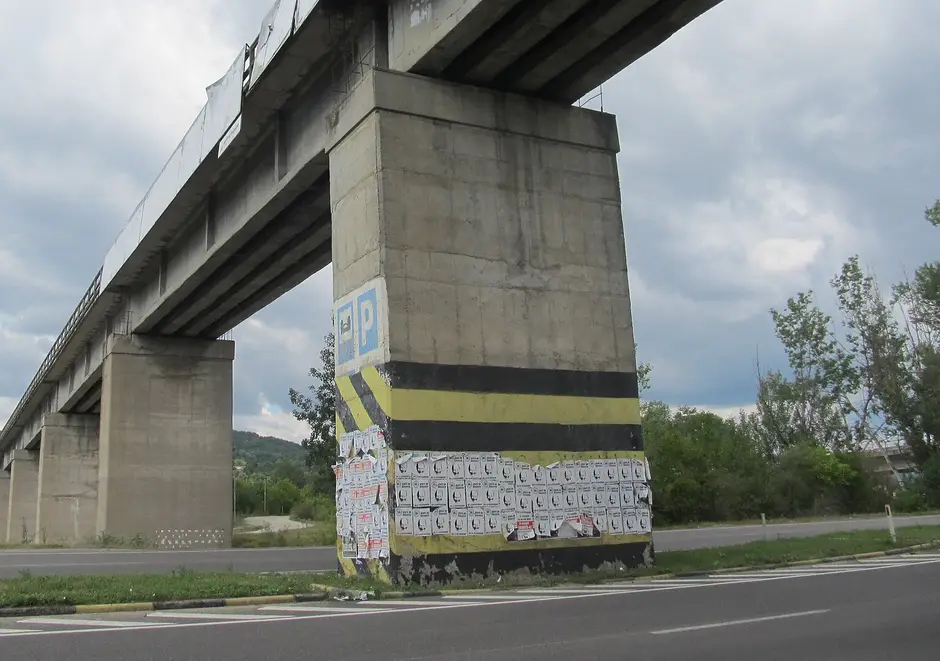 Pila podului fostei căi ferate Câmpina–Telega, la marginea DN1, marcată cu benzi și dungi oblice galben-negre.