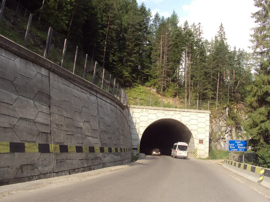 Zidul de sprijin de la intrarea în tunelul Lacu Roșu, pe DN12C, cu o bandă galben-neagră la bază; și marginile portalului au dungi oblice galben-negre.